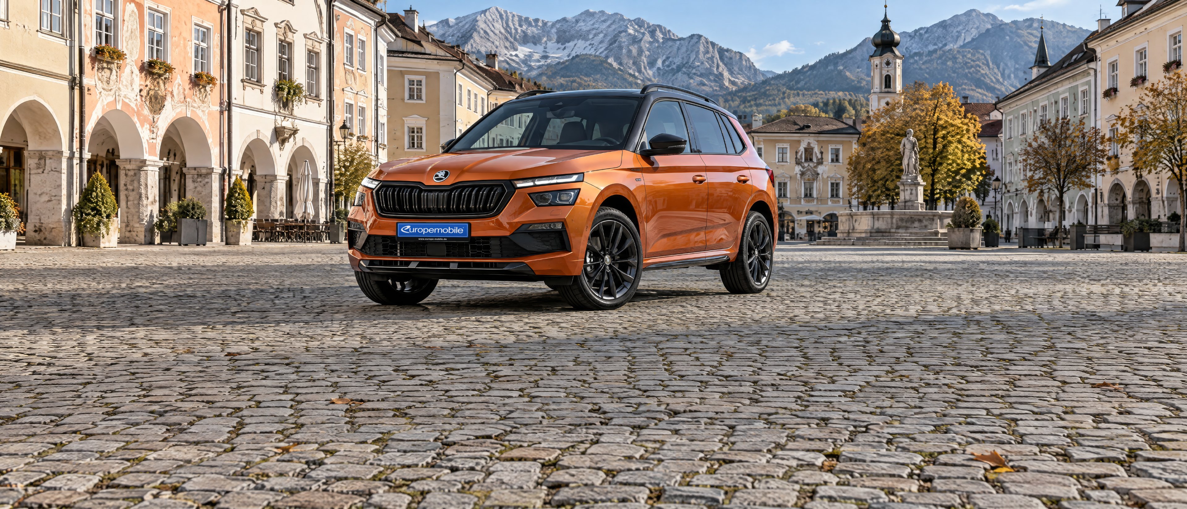 Škoda Kamiq in Orange auf einem Altstadt-Marktplatz in den Alpen