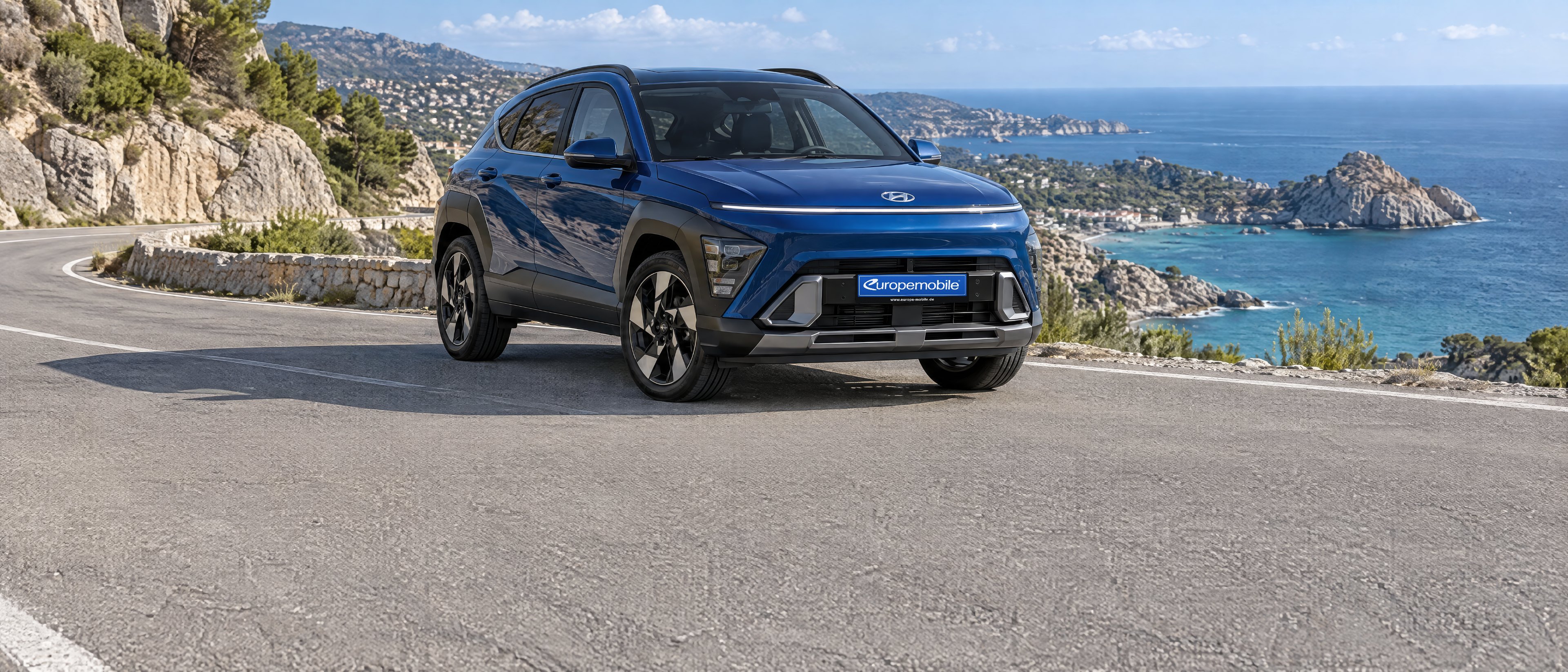 Hyundai Kona 2026 in Blau auf einer Küstenstraße am Meer