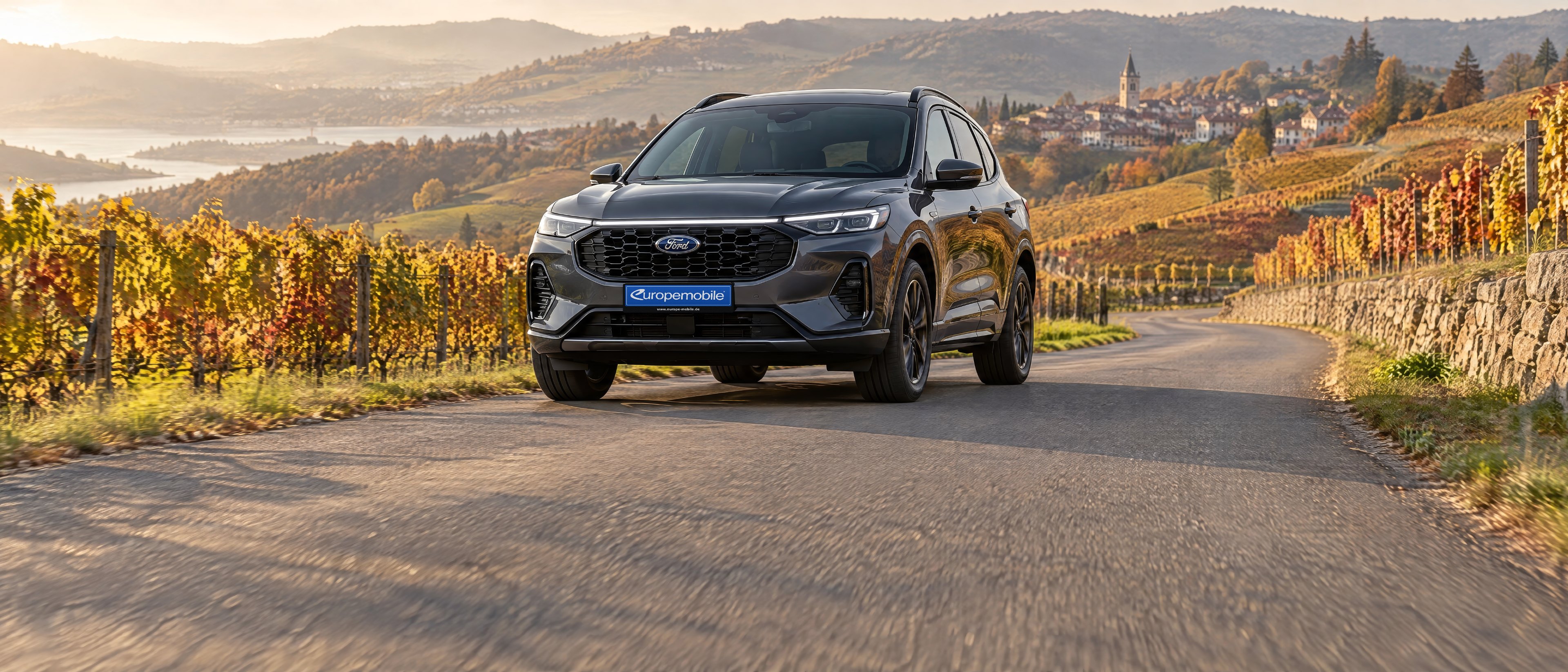Ford Kuga 2026 in Grau auf einer Straße durch herbstliche Weinberge