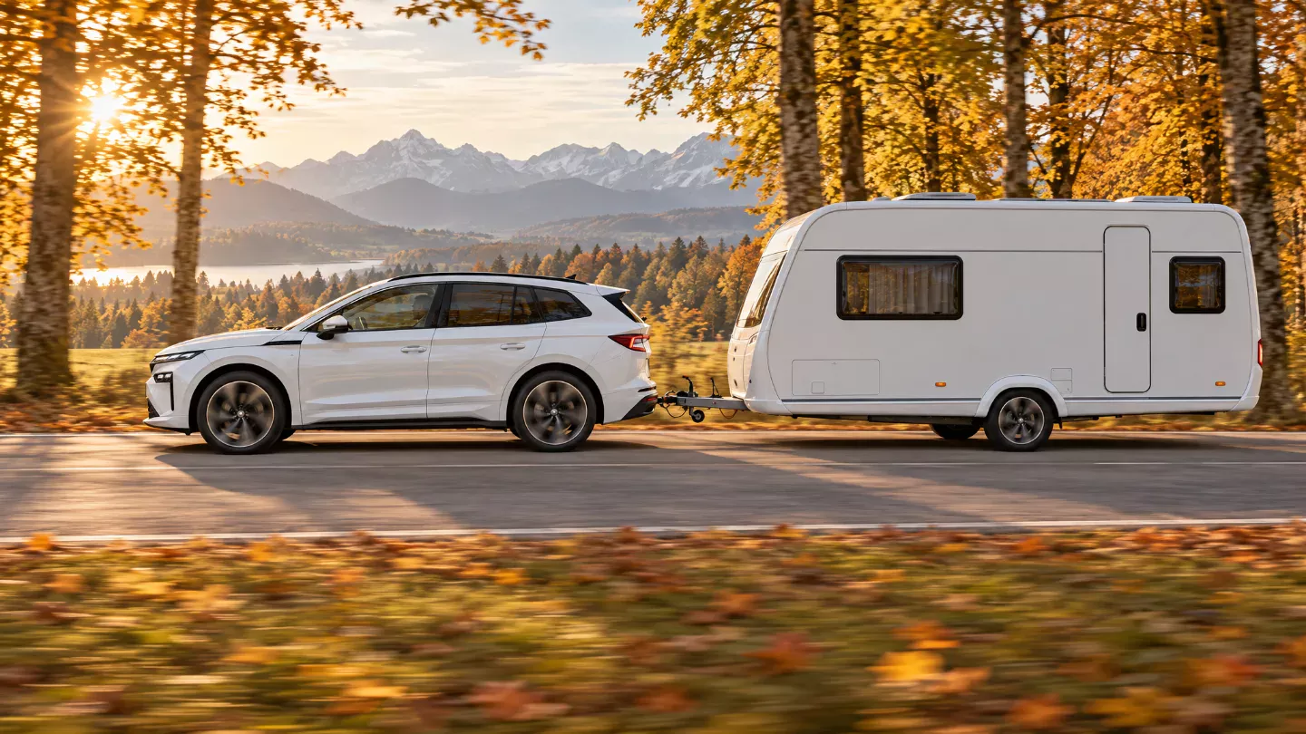 Škoda Enyaq 2026 mit Wohnwagen auf einer Herbstallee