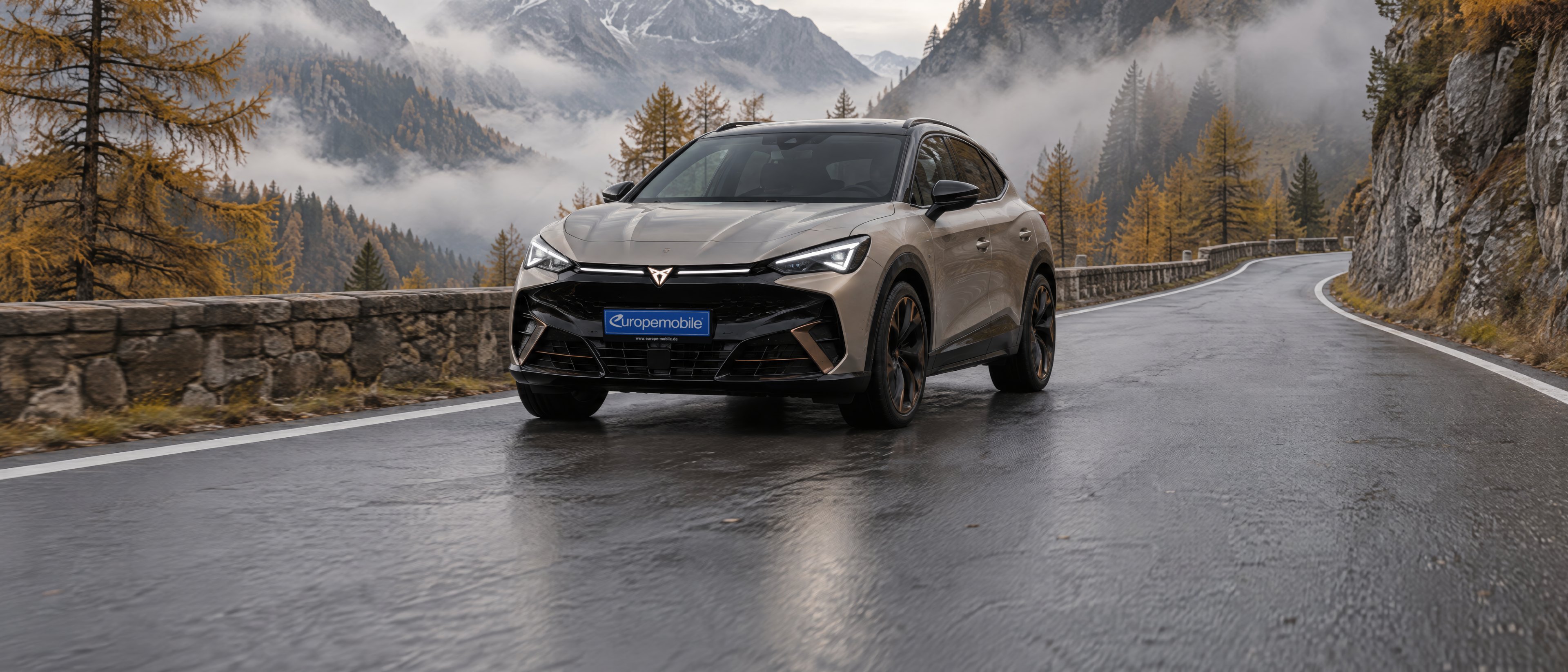 Cupra Tavascan 2026 in Sandbeige auf einer Passstraße im Herbstnebel